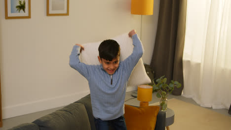 Disruptive-Young-Boy-Behaving-Badly-At-Home-Jumping-On-Sofa-And-Throwing-Cushions-Around-Lounge